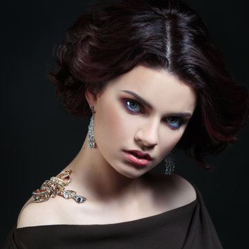 Portrait of wonderful girl on the shoulder which are gold and silver rings on a black background