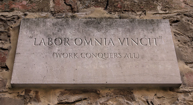 Labor omnia vincit. A Latin phrase meaning Work conquers all. Engraved text.