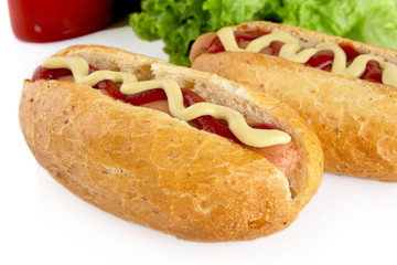 Hotdogs with ketchup with lettuce in the background on white