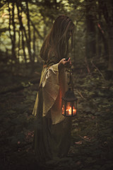 Woman walking in a forest with lantern