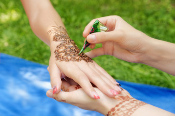 young woman mehendi artist painting henna on the hand