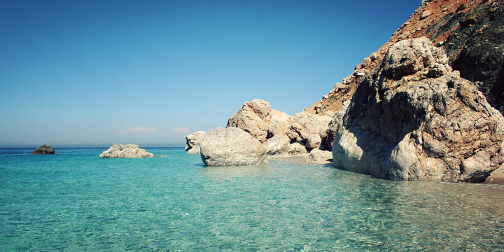 Calm blue sea and  rocks. Aged photo. Small island near Adrasan. Vintage effect image. Rocky shore. Toned photo. Antalya Province, Turkey. Wide photo for web site slider.