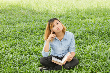Woman holding a book in meadows on the sunshine of morning.