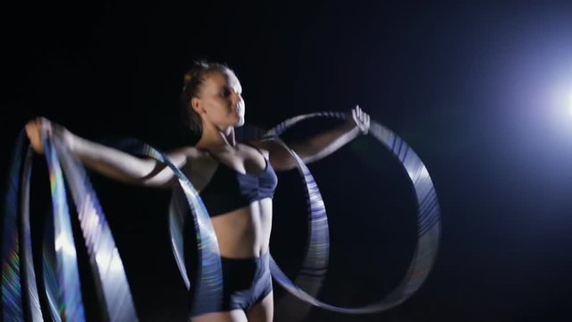 Professional female acrobatic performer rotate hula hoop on stage