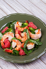 Shrimp, grapefruit and spinach salad in green plate