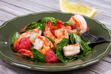 Shrimp, grapefruit and spinach salad in green plate