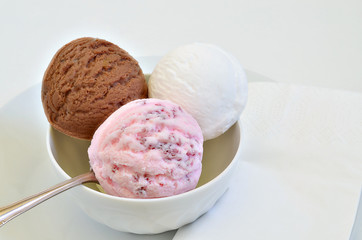 Schokoladeneis, Vanilleeis und Erdbeereis / Eiscreme, Eiskugel, Schokolade, Vanille und Erdbeere in einer Schale, Serviette, weiß, pink, braun, Makro, weißer Hintergrund, horizontal