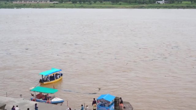Small open boats crossing river with muddy water in India