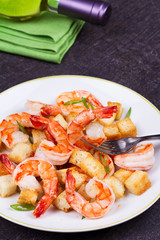 Shrimp with crispy croutons and scallions in white plate. White wine bottle