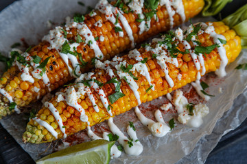 Grilled corn cobs on wooden plate, mexican style, close view