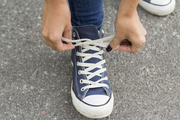 Hands girl with beautiful manicure knotted the laces on your shoelace.