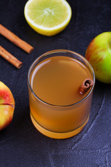 Cider glass with apples, lemon and cinnamon on black background