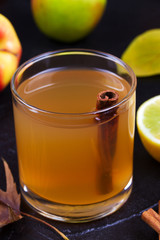 Cider glass with apples, lemon and cinnamon on black background