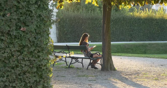 Woman reads electronic reder in the park on the bench