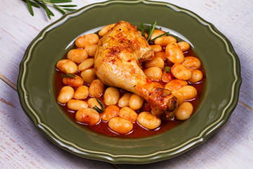 Chicken and white bean in tomato sauce with rosemary in frying pan on white wooden background