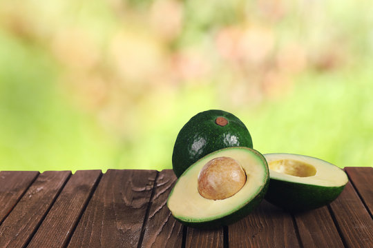 Fresh avocados on the table, on blurred nature background