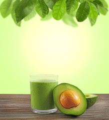 Glass of fresh avocado cocktail on table in front  blurred nature background