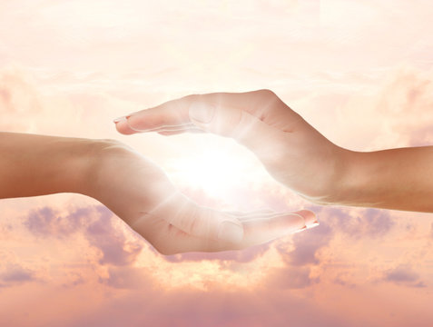 Female hands holding sunlight on sky background.