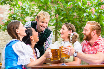 Vier Freunde trinken gleichzeitig Bier im Biergarten in Bayern