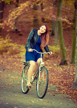 Redhead lady cycling in park.