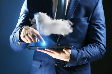 Businessman using tablet on blue background. Cloud computing and information storage concept.