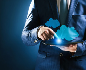 Businessman using tablet on blue background. Cloud computing and information storage concept.