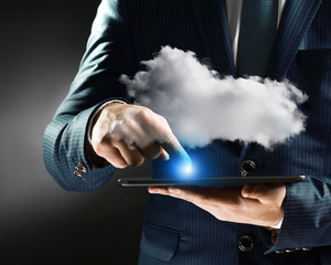 Businessman using tablet on gray background. Cloud computing and information storage concept.