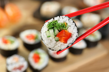Tasty sushi with chopsticks, closeup