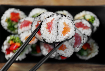 Tasty sushi roll with black chopsticks, top view