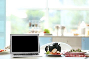 Laptop, tasty dish and camera on kitchen table. Food blogger concept
