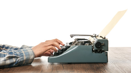 Man working on retro typewriter at desk on white background