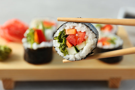Tasty suhsi roll with wooden chopsticks, closeup