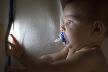 Baby using mobile phone on the crib at night