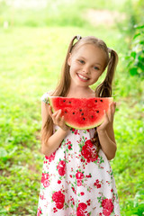 Smiling little girl with blue eyes eats a slice of watermelon