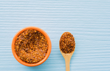 Cayenne pepper in wood spoon and bowl on table