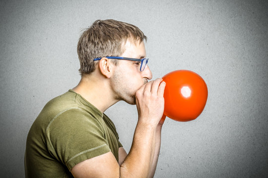 Junger Mann pustet Ballon auf