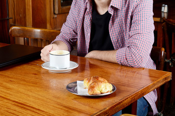Young man with laptop and cup of coffee.