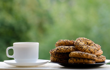 A mug of coffee and a plate of delicious cookies on the table, green background