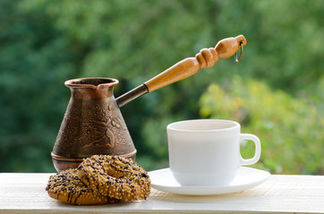 Coffee Mug, two cookies and copper Cezve on the desk of street cafes