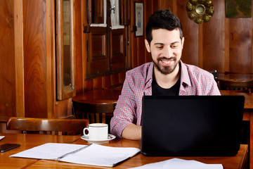 Latin student using laptop with cup of coffee.