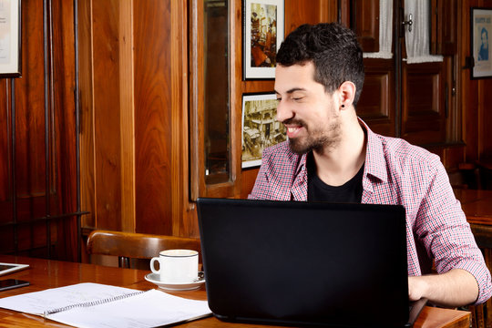 Latin student using laptop with cup of coffee.