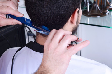 Young man having a haircut with scissors.