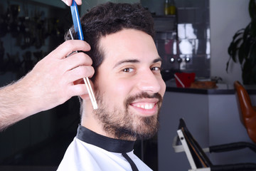 Young man having a haircut with straight razor.