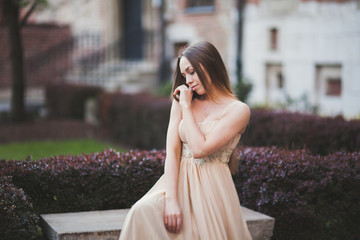 Fototapeta premium Beautiful happy woman in park a warm spring day sitting on the bench