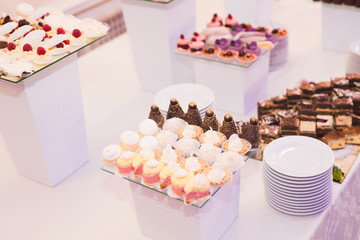 Delicious and tasty dessert table with cupcakes shots at reception closeup