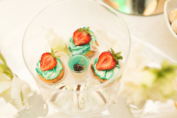 Delicious and tasty dessert table with cupcakes shots at reception closeup