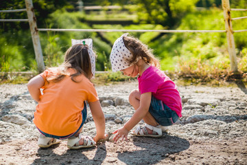 two little girls are playing with stones