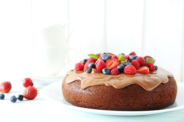 Homemade chocolate cake with berries on white wooden table
