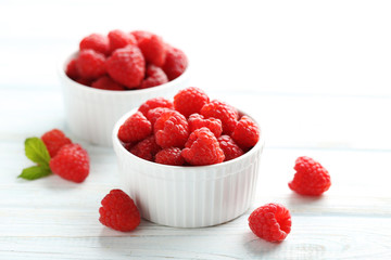 Red raspberries in bowl on a white wooden table