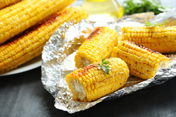 Tasty grilled corn on grey wooden table